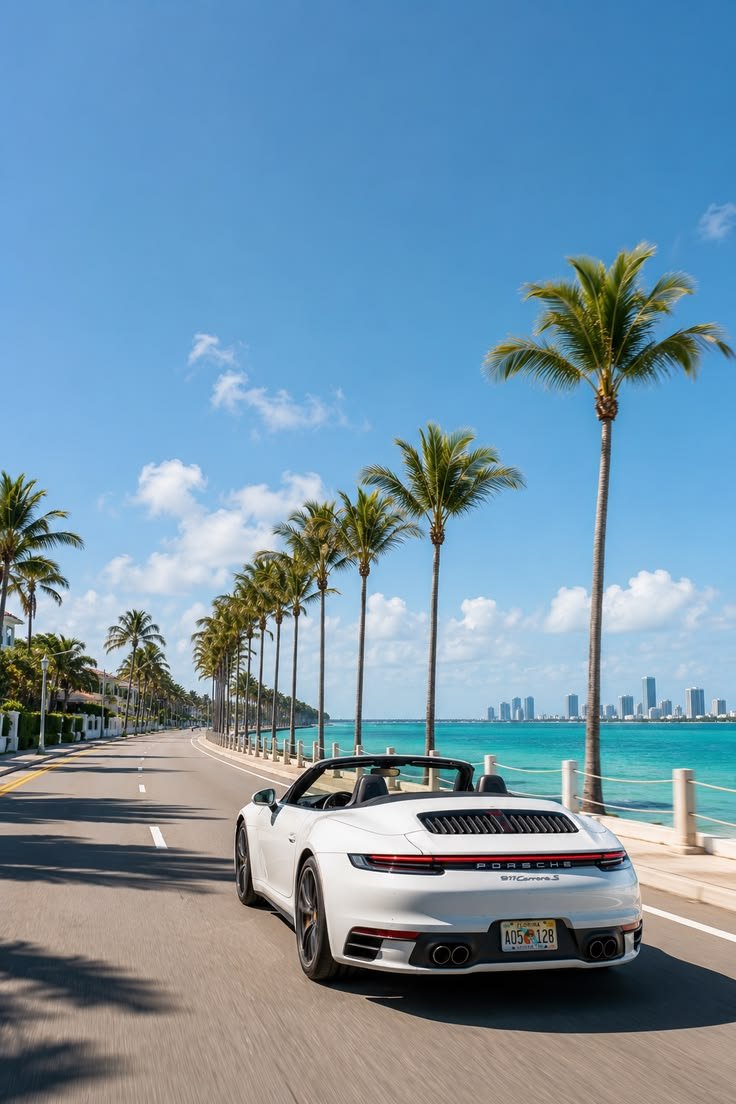 A white Porsche 911 Cabriolet driving along a…